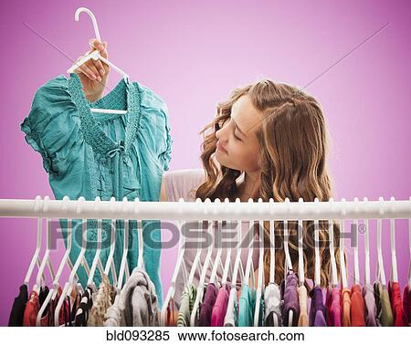 Stock Photography - Caucasian teenager looking at shirt. Fotosearch