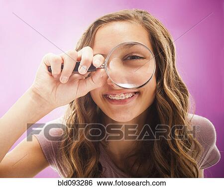 Stock Photograph - Caucasian teenager peering through magnifying glass. Fotosearch