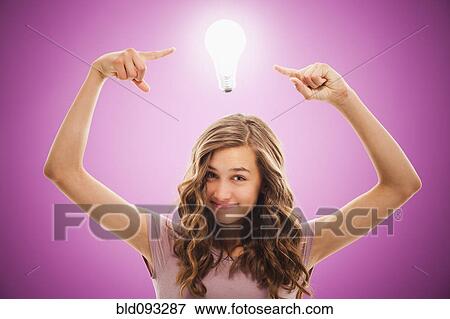 Stock Photo - Caucasian teenager pointing at light bulb over her head. Fotosearch