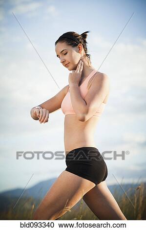 Stock Image - Caucasian woman checking her pulse after exercise. Fotosearch