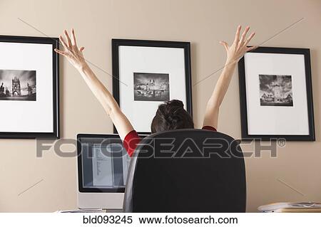 Stock Photography - Caucasian woman cheering at desk in home office. Fotosearch