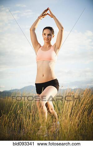 Stock Image - Caucasian woman exercising in field. Fotosearch