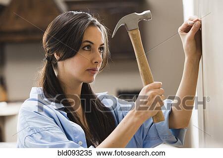 Caucasian woman hammering nail into wall View Large Photo Image Stock Photography - Caucasian woman hammering nail into wall. Fotosearch