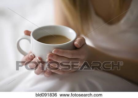 Stock Photograph - Caucasian woman holding cup of coffee. Fotosearch