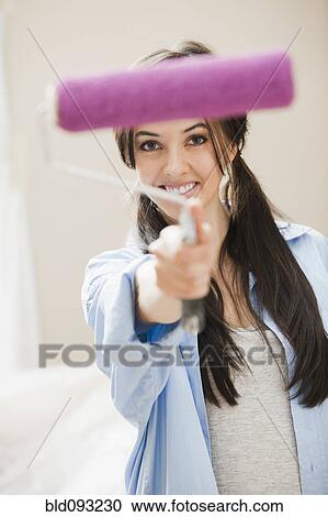 Stock Image - Caucasian woman holding paint roller. Fotosearch