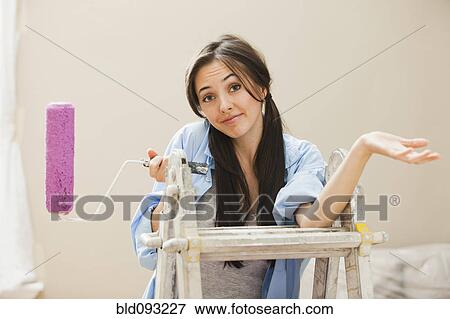 Stock Photo - Caucasian woman holding paint roller. Fotosearch