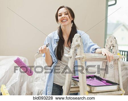 Stock Photo - Caucasian woman holding paint roller. Fotosearch