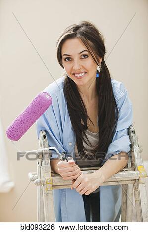 Stock Photograph - Caucasian woman holding paint roller. Fotosearch