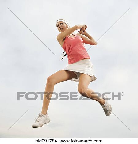 Caucasian woman jumping in mid-air playing tennis View Large Photo Image Picture - Caucasian woman jumping in mid-air playing tennis. Fotosearch