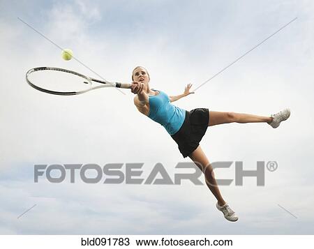 Caucasian woman jumping in mid-air playing tennis View Large Photo Image Stock Image - Caucasian woman jumping in mid-air playing tennis. Fotosearch