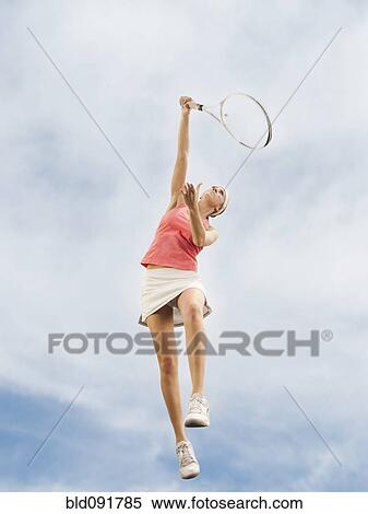 Caucasian woman jumping in mid-air playing tennis View Large Photo Image Stock Photography - Caucasian woman jumping in mid-air playing tennis. Fotosearch
