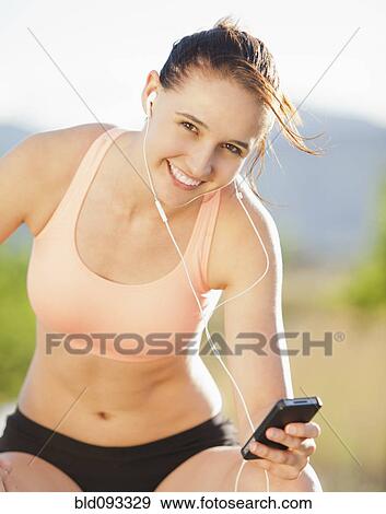 Stock Photo - Caucasian woman listening to music and exercising. Fotosearch