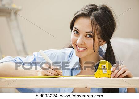 Picture - Caucasian woman measuring wood. Fotosearch