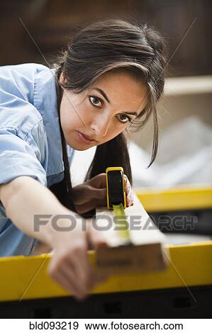 Stock Photo - Caucasian woman measuring wood. Fotosearch