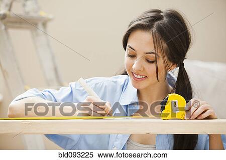 Stock Photography - Caucasian woman measuring wood. Fotosearch