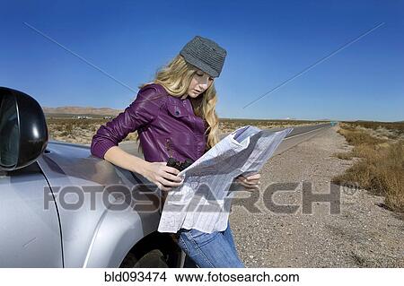 Picture - Caucasian woman reading map at roadside. Fotosearch