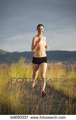 Stock Photo - Caucasian woman running on remote path. Fotosearch