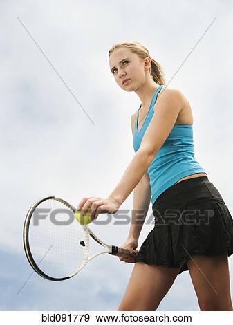 Stock Photo - Caucasian woman serving tennis ball. Fotosearch