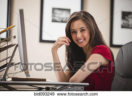 Stock Photo - Caucasian woman sitting at desk in home office. Fotosearch