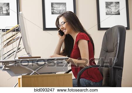 Stock Photo - Caucasian woman talking on phone at desk in home office. Fotosearch