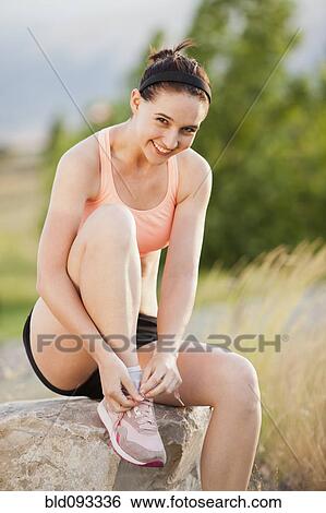 Stock Photograph - Caucasian woman tying her shoes. Fotosearch