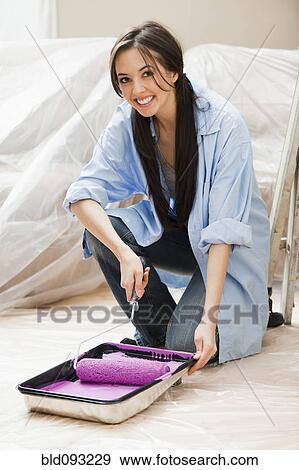 Stock Photo - Caucasian woman using paint roller. Fotosearch