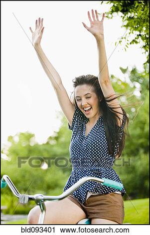 Stock Image - Cheering Caucasian woman cheering on bicycle. Fotosearch