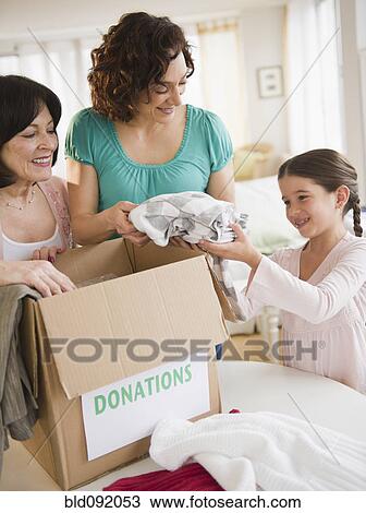 Stock Image - Family packing box of clothing donations. Fotosearch