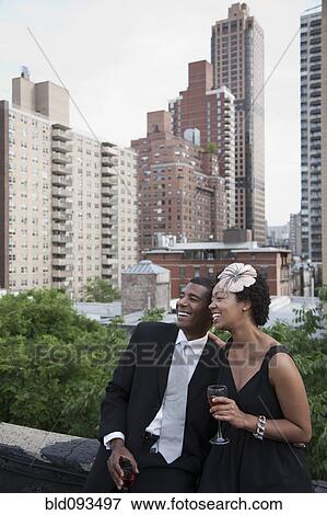 Stock Photo - Glamorous African American couple drinking wine on rooftop. Fotosearch