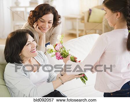 Stock Photo - Granddaughter giving grandmother bouquet of flowers. Fotosearch