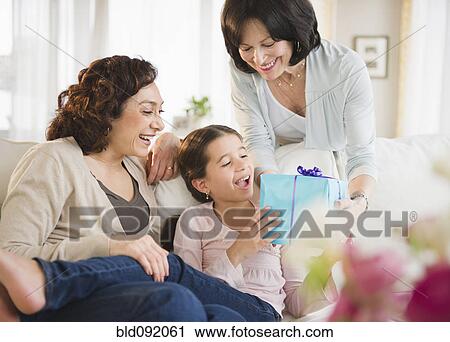 Stock Image - Grandmother giving granddaughter birthday gift. Fotosearch