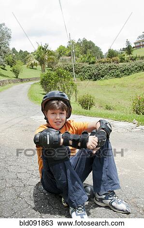 Hispanic boy in pads and helmet sitting on skateboard View Large Photo Image Stock Image - Hispanic boy in pads and helmet sitting on skateboard. Fotosearch