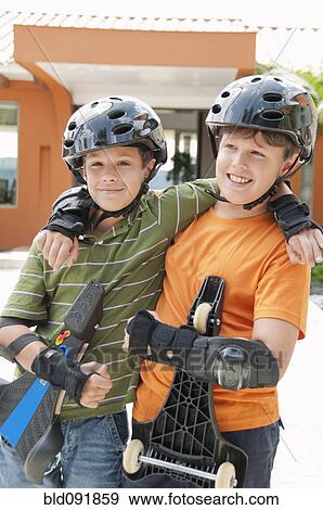 Stock Photo - Hispanic boys in pads and helmets holding skateboards. Fotosearch