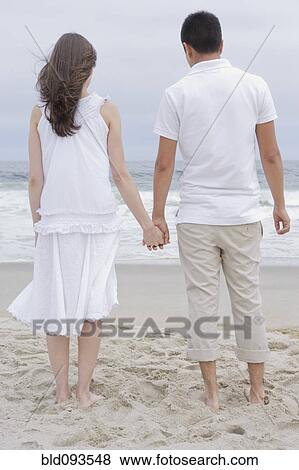Stock Photo - Hispanic couple holding hands on beach. Fotosearch