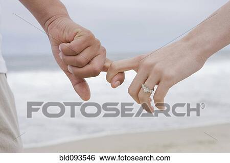 Stock Photograph - Hispanic couple holding hands on beach. Fotosearch