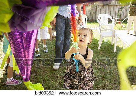 Stock Image - Hispanic girl trying to hit pinata. Fotosearch