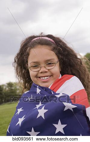 Stock Image - Hispanic girl wrapped in American flag. Fotosearch