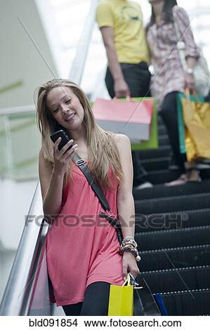 Hispanic woman text messaging on escalator View Large Photo Image Picture - Hispanic woman text messaging on escalator. Fotosearch