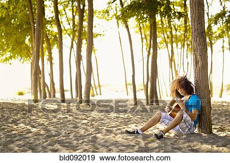 Mixed race teenager sitting in sand strumming guitar View Large Photo Image Stock Photo - Mixed race teenager sitting in sand strumming guitar. Fotosearch