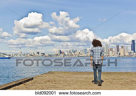 Stock Image - Mixed race teenager standing at urban waterfront. Fotosearch