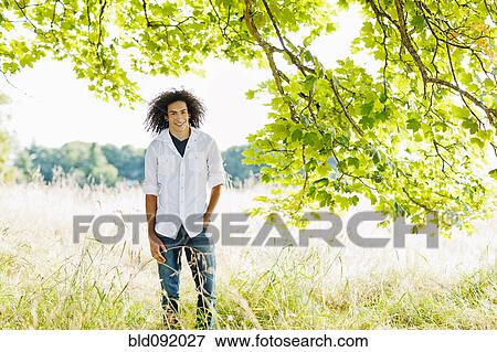 Stock Photo - Mixed race teenager standing in remote field. Fotosearch