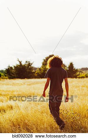 Stock Photo - Mixed race teenager walking in remote field. Fotosearch