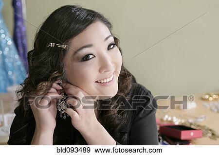 Mixed race woman putting on earrings View Large Photo Image Stock Photo - Mixed race woman putting on earrings. Fotosearch