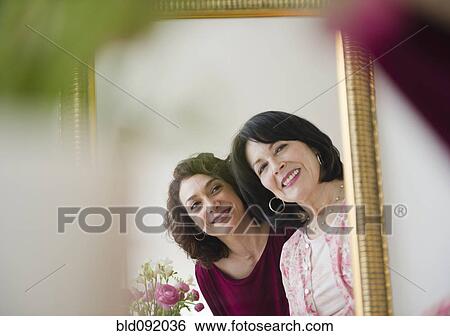 Stock Photograph - Mother and daughter looking in mirror. Fotosearch