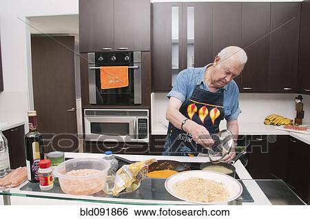 Stock Photograph - Senior Hispanic man cooking in kitchen. Fotosearch