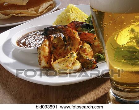 Stock Image - Shrimp entree and glass of beer. Fotosearch