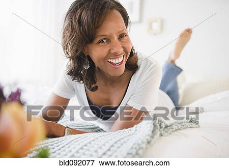 Smiling Black woman laying on bed View Large Photo Image Stock Photo - Smiling Black woman laying on bed. Fotosearch