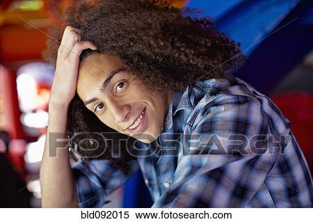 Stock Photography - Smiling mixed race teenager with head in hands. Fotosearch