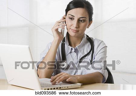 Turkish doctor talking on cell phone and using laptop View Large Photo Image Stock Photograph - Turkish doctor talking on cell phone and using laptop. Fotosearch