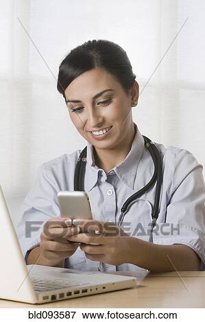Stock Photo - Turkish doctor text messaging on cell phone. Fotosearch